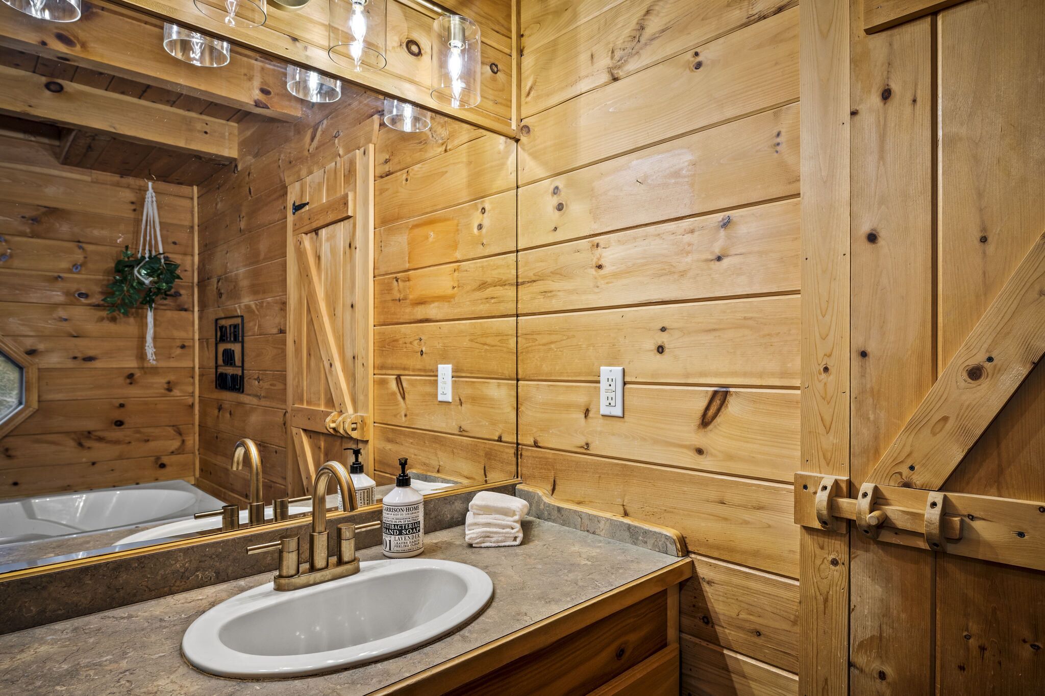Une salle de bain rustique, avec une cabine en bois, un lavabo, un miroir et un porte-serviettes.