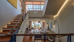Un amplio salón con una escalera que lleva a un balcón.