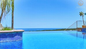 Una piscina infinita azul cristalina, con vista al océano y una isla distante.