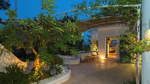 An outdoor patio area with a covered seating area, a dining table, and a view of the interior of the building. - Son de Mar - By Almarina Villas (JÁVEA)