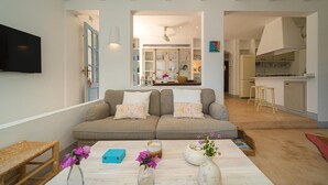 A living room with a sofa, a coffee table with decorative items, a television, and a kitchen area in the background. - Son de Mar - By Almarina Villas (JÁVEA)