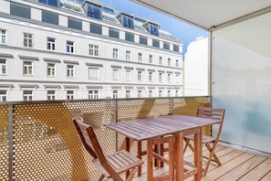 Enjoy the view from this balcony with a table and chairs.