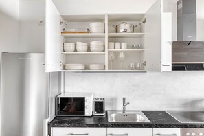 Een moderne keuken met witte kasten, een ingebouwde magnetron, een roestvrijstalen spoelbak en een afzuigkap.