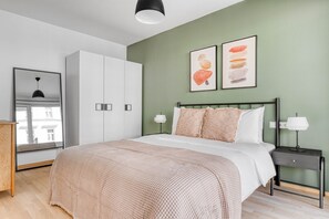 Quarto moderno com cama, mesas de cabeceira, guarda-roupa e obras de arte na parede.