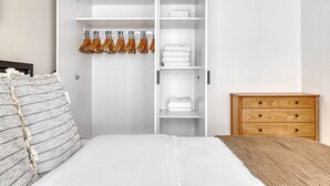 A bedroom with a bed, a wardrobe with hanging clothes, and a wooden dresser. - Sunny Brigittenau 1BR w/ Elevator & Storage, nr Augarten, by Blueground (Vienna)
