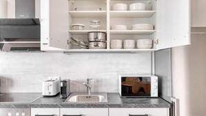 A modern kitchen with white cabinetry, a built-in microwave, a stainless steel sink, and a toaster. - Sunny Brigittenau 1BR w/ Elevator & Storage, nr Augarten, by Blueground (Vienna)