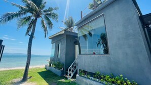 Edifício moderno à beira-mar, com uma janela grande, um pequeno terraço e vista para o mar.