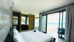 Quarto de hotel moderno com uma cama grande, uma escrivaninha e vista para o mar.
