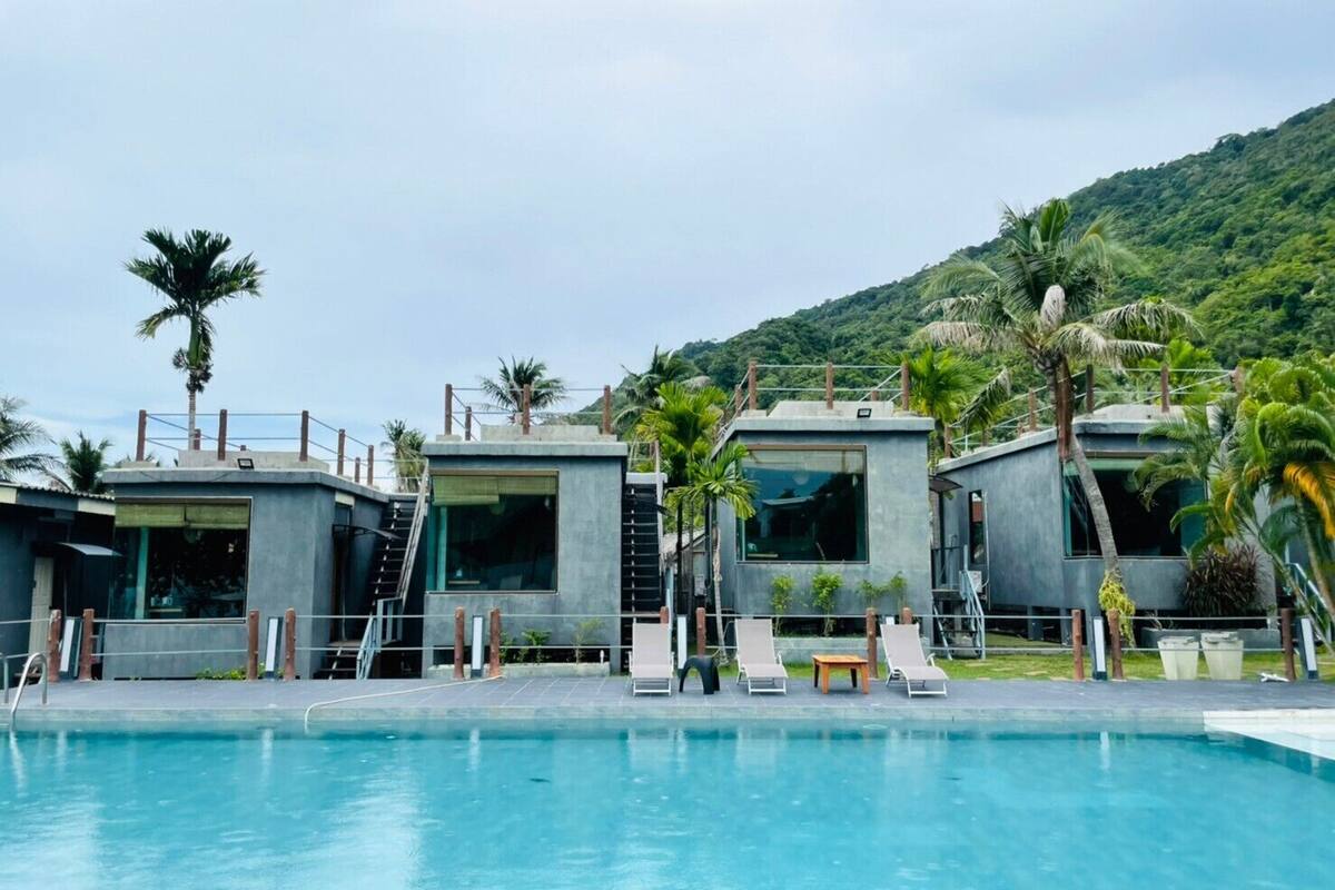 A modern pool area with lounge chairs and a clear view of a mountainous landscape in the background.