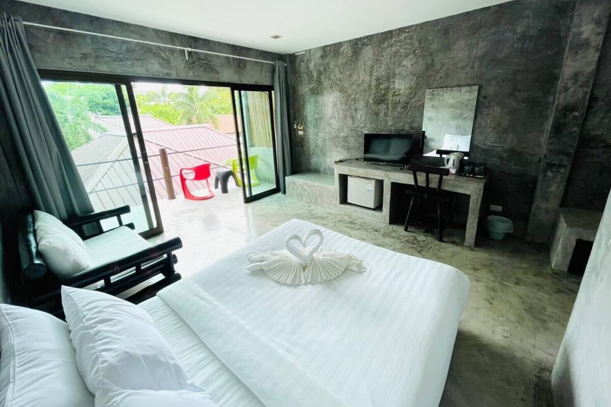 A modern hotel room with a large bed, a desk with a computer, and a TV.