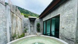 Uma área de spa com hidromassagem, chuveiro envidraçado e vista para uma paisagem montanhosa.