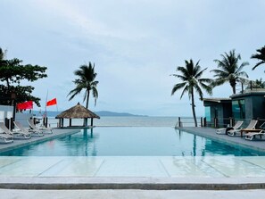 A pool area with lounge chairs, a thatched hut, and palm trees. - The Sea Resort Haad Rin (Ko Pha-ngan)