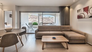 A modern living room with a sofa, a coffee table, and a dining area with chairs and a table.