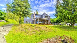 A modern house with a covered porch, surrounded by lush greenery and a clear blue sky. - Stunning Hood Canal Getaway w/ Private Deck! (Belfair)