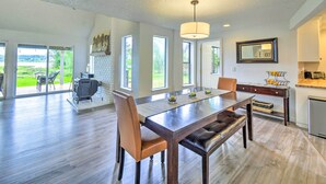 A spacious dining area with a long table, chairs, and a bench. There is a fireplace and a view of the outdoors. - Stunning Hood Canal Getaway w/ Private Deck! (Belfair)