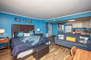 A bedroom with a bed, bedside table, and a sofa with a 'Blessed' sign.
