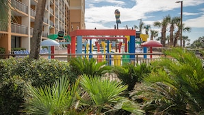 Ein Hotel mit Poolbereich, Palmen und einer Spielanlage.