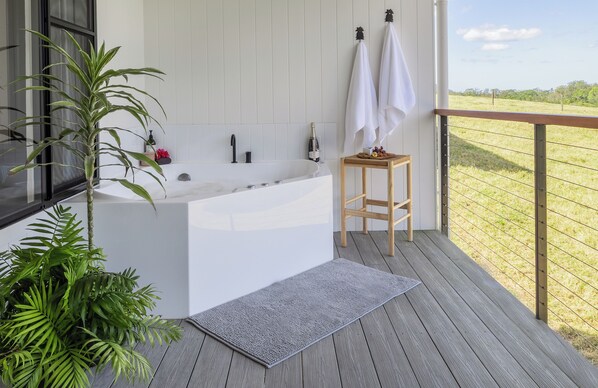 Un baño moderno con una bañera independiente, un taburete de madera y una planta en maceta.