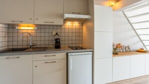 A modern kitchen with a dishwasher, a coffee machine, and a built-in oven.