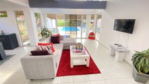 Un salon moderne avec un canapé gris, un tapis rouge et un téléviseur fixé au mur.