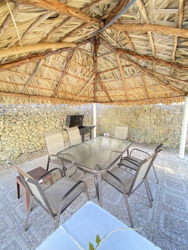 Relax in the shaded seating area with a central table and metal chairs, surrounded by a stone wall.
