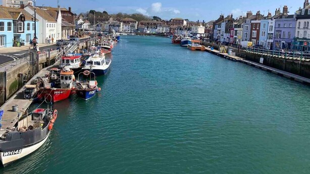 A harbor with boats docked along the piers, a George Inn building, and a row of colorful townhouses. - Harbourside - Luxury 2Bed Cottage & Garden (Weymouth)