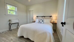 Quarto com cama, ventoinha no teto, janela e uma cadeira.