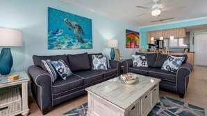 Uma sala de estar com dois sofás, uma mesa de centro e um quadro de tartaruga marinha.