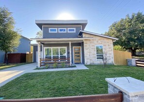 Enter a charming home with a glass door and double doors, surrounded by a well-maintained lawn and a tree-lined street.