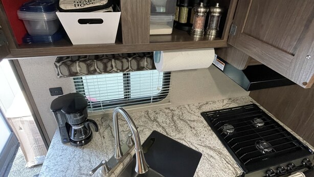 A compact kitchen with a sink, stove, and coffee maker. - Spacious RV w/ large shower & Queen bed (Pacific)