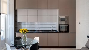 Een moderne keuken met inbouwapparatuur, een glazen eettafel en een vaas zonnebloemen.