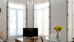 Een moderne woonkamer met een flatscreen televisie, een glazen eettafel en een bank.