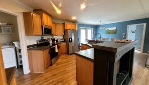 A modern kitchen with wooden cabinets, stainless steel appliances, and a granite countertop. - Secluded cabin on a horse farm, bordered by the North River (GROTTOES)