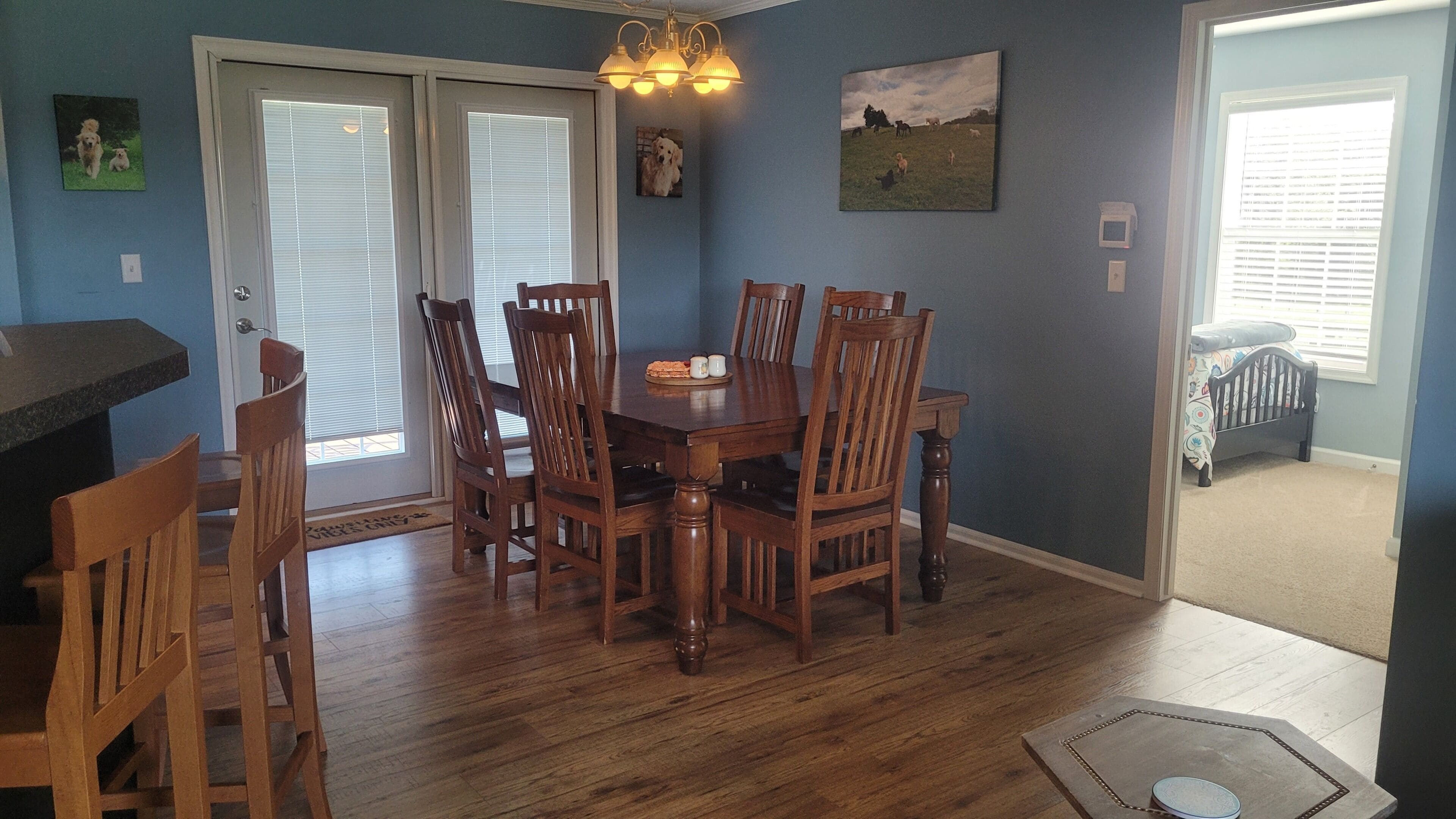 A dining area with a wooden table and chairs, a chandelier, and a painting on the wall.