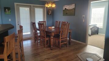 A dining area with a wooden table and chairs, a chandelier, and a painting on the wall.