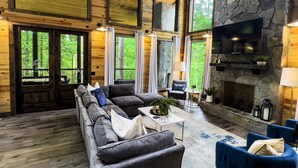 A spacious living room with a stone fireplace, large windows, and a comfortable seating area.