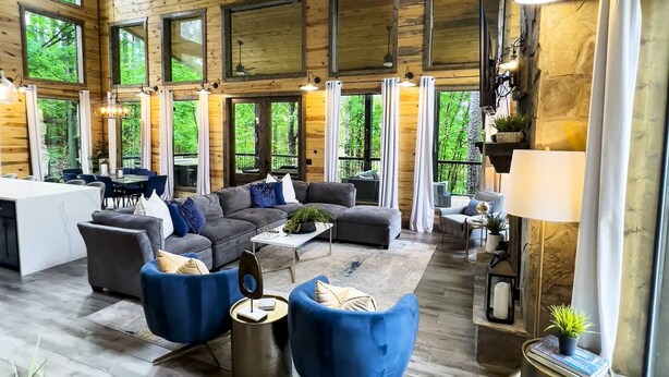 A spacious living area with a high ceiling, large windows, and a modern fireplace.