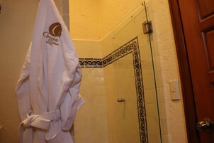 Un baño con cabina de ducha de vidrio, una toalla blanca con un logotipo y una puerta de madera.