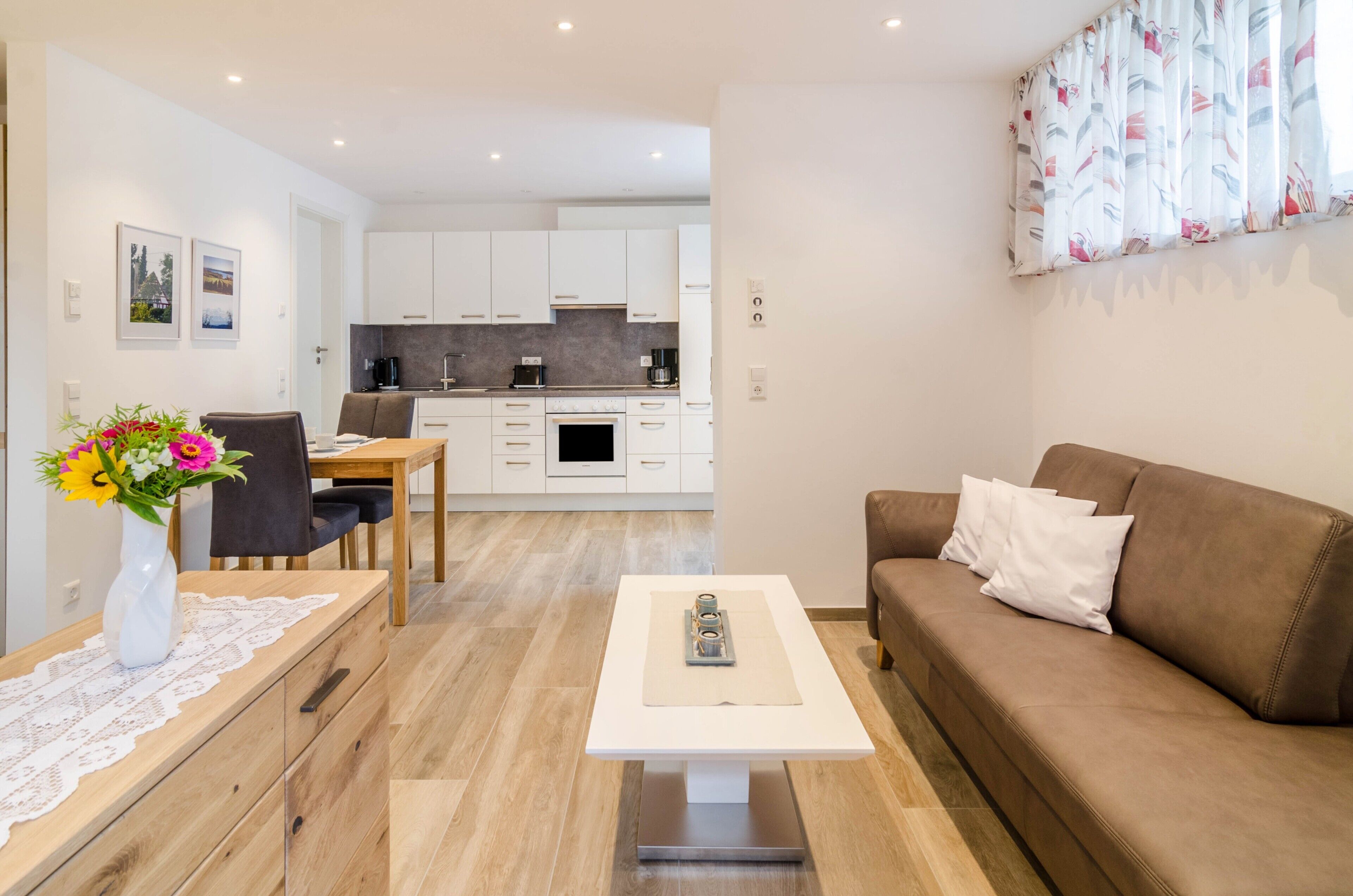 Un salon moderne avec un canapé marron, une table basse et un coin repas comprenant une table et des chaises.