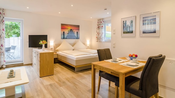 Een moderne kamer met een bed, een eettafel, een televisie en kunstwerken aan de muren.