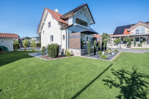 A two-story house with a red-tiled roof, a covered porch, and a well-maintained lawn. - Holiday Home "Bezauberndes Gästehaus" with Terrace & Wi-Fi (Zaisertshofen)