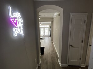 Stylish hallway with a neon sign reading 'Love life get' and a white door leading to a space.