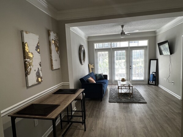 Relax in this stylish living room with a large window, sofa, coffee table, and flat-screen TV.