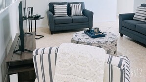 Een moderne woonkamer met twee banken, een salontafel en een tv-meubel.