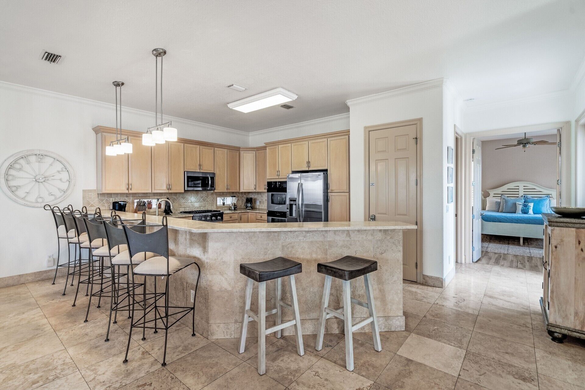 A spacious kitchen with a central island, bar stools, and modern appliances.