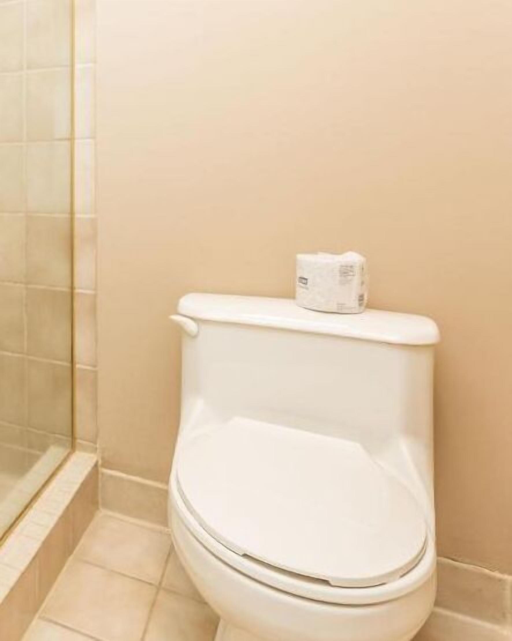 A white toilet in a bathroom with beige walls and tiled flooring.