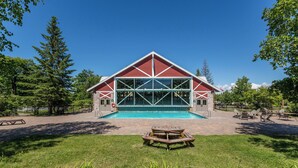 Un edificio con un'ampia facciata vetrata, una piscina e un'area picnic.