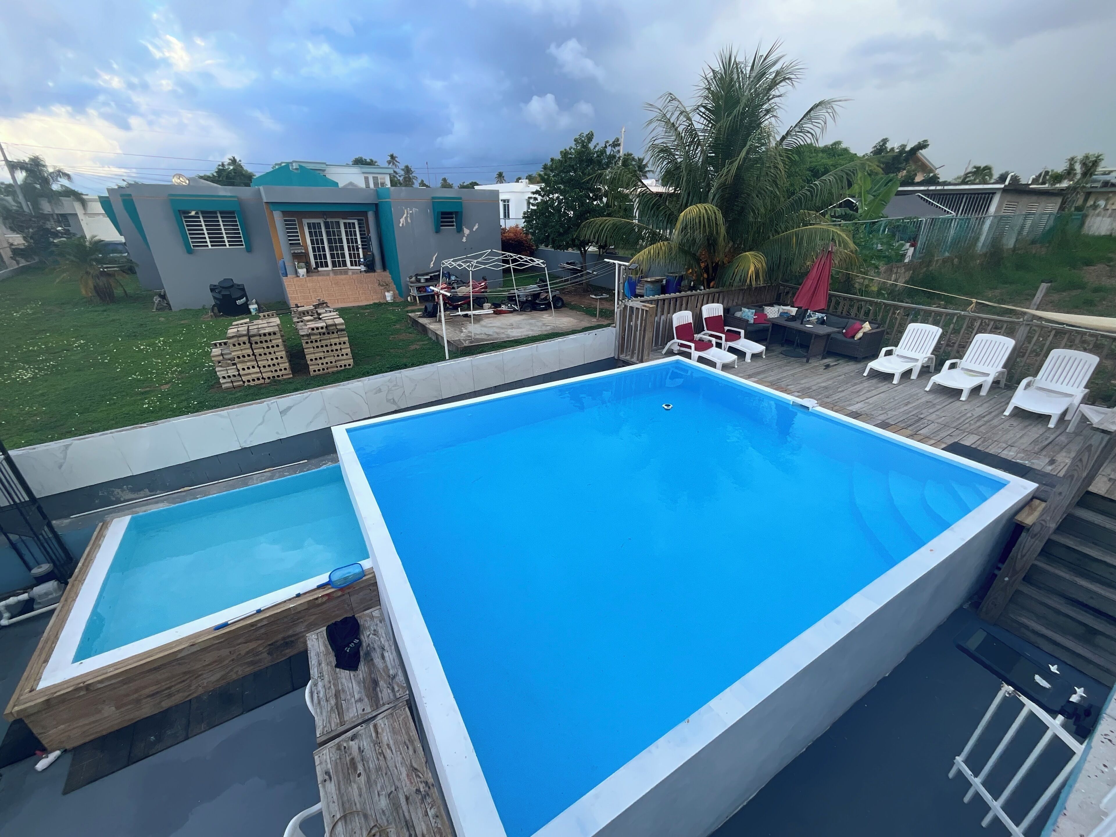 A rectangular swimming pool with a wooden deck and a smaller adjacent pool.