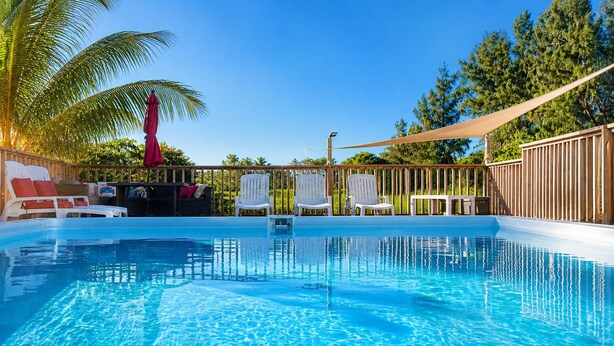 A swimming pool with lounge chairs and a wooden fence. - Jobos Luxury Condos (Isabela)