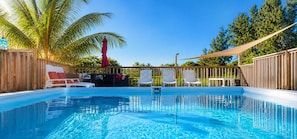 A swimming pool with lounge chairs and a wooden fence.